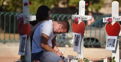 Amigos de una de las víctimas de la matanza de Las Vegas, junto a una cruz en su honor.