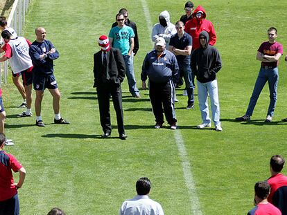 Los <i>ultras,</i> con Fran, el del traje, y Portu, con gorra, al frente insultando a los jugadores ante la mirada reprobatoria de Bastón, cruzado de brazos.