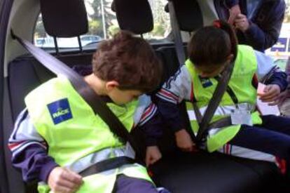 Dos niños se abrochan el cinturón de seguridad, en la escuela de educación vial itinerante de RACE-Renault. EFE/Archivo