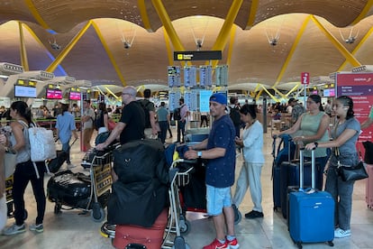 Varias personas hacen cola en la zona de facturación de la T-4 del aeropuerto Adolfo Suárez de Madrid tras la incidencia informática global, este viernes.