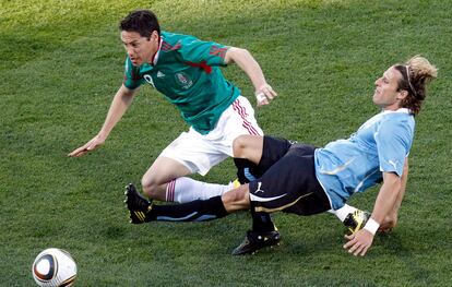 El futbolista mexicano Guillermo Franco lucha por el balón con el uruguayo Diego Forlán.