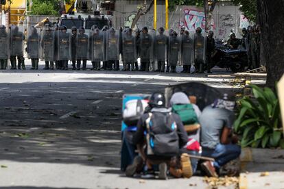 Manifestantes opositores se refugian en sus escudos frente a miembros de la Guardia Nacional Bolivariana en Caracas .