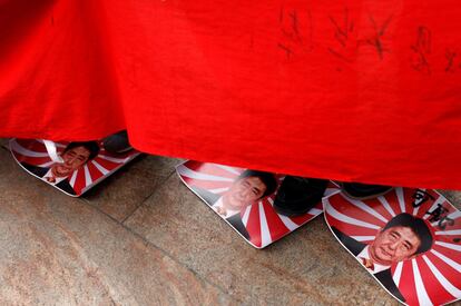 Los manifestantes pisan las imágenes de la bandera del Sol Naciente con el retrato del primer ministro de Japón, Shinzo Abe, en el 80º aniversario de la masacre de Nanjing, en Hong Kong (China).