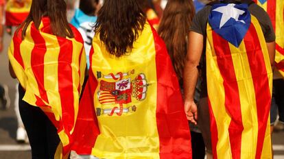 Tres j&oacute;venes acuden a una manifestaci&oacute;n en Barcelona con una estelada, una senyera y una bandera de Espa&ntilde;a.