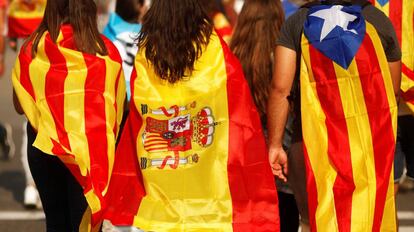 Tres jóvenes acuden a una manifestación en Barcelona con una estelada, una senyera y una bandera de España.