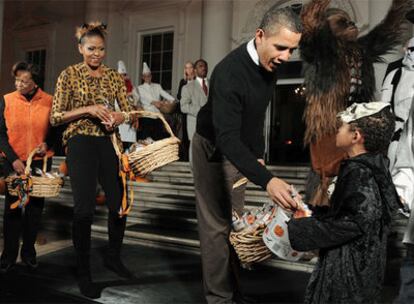 El presidente de EE UU, Barack Obama, y su esposa Michelle, reparten caramelos en la Casa Blanca.