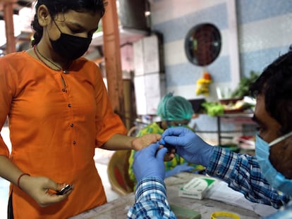 Un sanitario toma una muestra de sangre a una joven para detectar malaria y dengue en Mumbai.