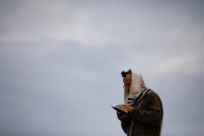 Un soldado israelí reza subido a la parte superior de un tanque situado en la zona occidental de Galilea, cerca de la frontera norte de Israel con Líbano, este lunes.