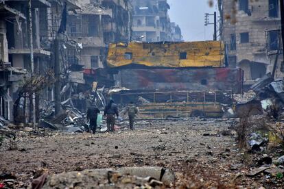 Forças pró-governo caminham no devastado bairro de Bustan Al-Qasr, em Aleppo, em 13 de dezembro