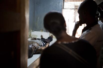 Aspasia Tanis y su hermano observan el cuerpo de su padre fallecido en la funeraria Zenith en Puerto Príncipe, Haití. Tanis busca frenéticamente préstamos de amigos y pastores para pagar el funeral más barato que se ofrece.