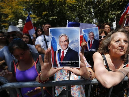 A woman holds a photograph of Sebastián Piñera as she waits for the arrival of his coffin in front of the Old Congress, in Santiago, on Wednesday, February 7.