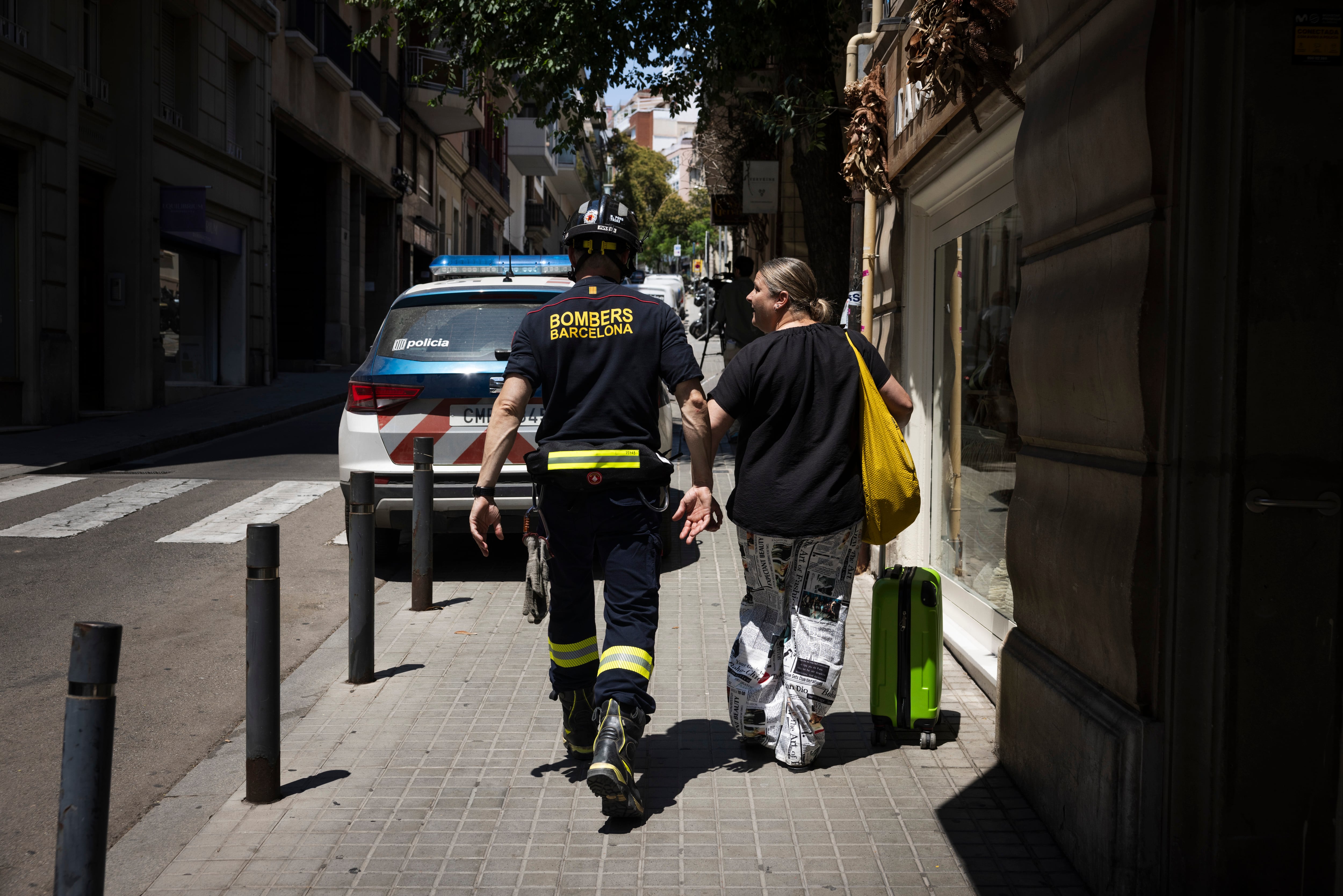 Una vecina desalojada tras el socavón acompañada de un bombero, el día del socavón, en julio.