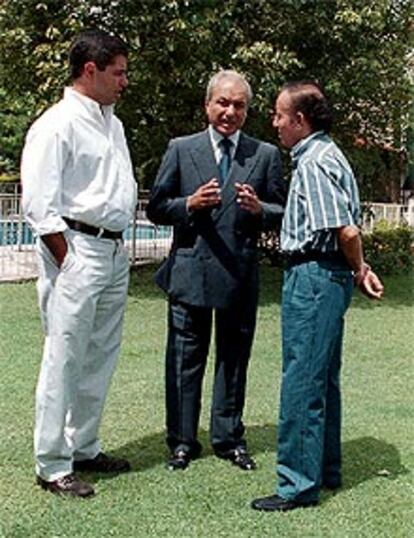 Menem (derecha) habla con su hermano Eduardo (centro) y su sobrino Adrián, en los jardines de la casa donde se encuentra bajo arresto.