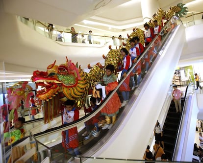 Intérpretes de la danza del Dragón, parte esencial de las celebraciones del Año Nuevo chino, descienden por la escalera mecánica de un centro comercial de Bangkok, Tailandia.