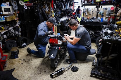 Empleados realizan mantenimiento a un scooter dentro de la tienda de scooters El Rey de las Motos