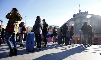 Un grupo de viajeros esperan en el exterior de la estación de Atocha tras ser desalojados por una amenaza de bomba.