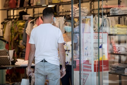 Una empleada toma la temperatura a un cliente en una tienda de moda de Barcelona.