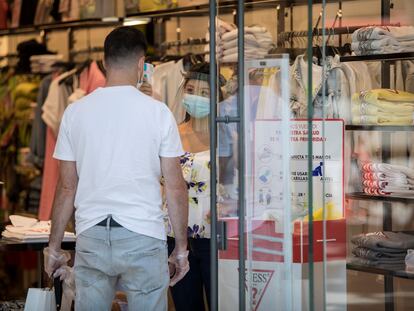 Una empleada toma la temperatura a un cliente en una tienda de moda de Barcelona.