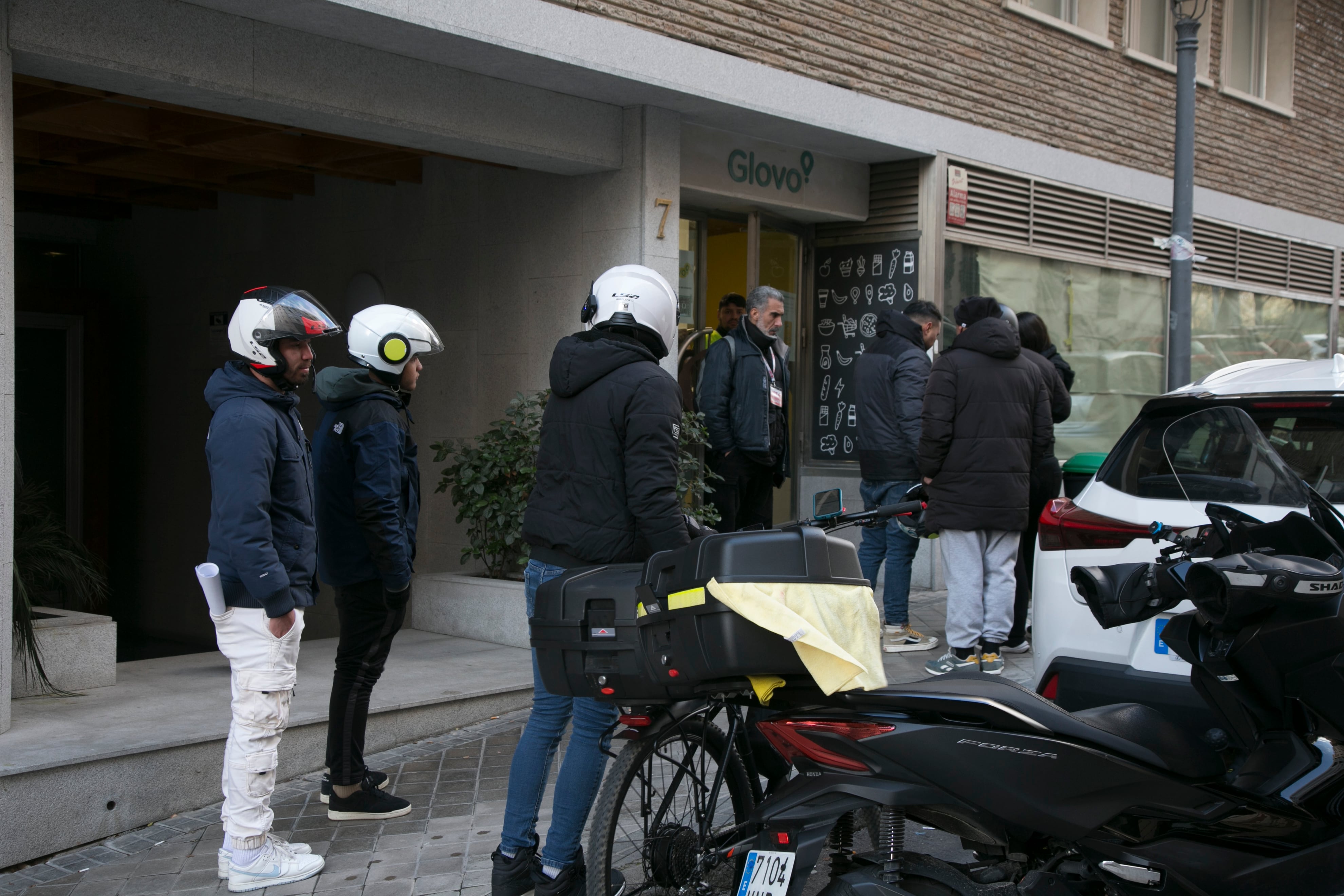 Varios repartidores frente a un local de Glovo en Madrid, este sábado.