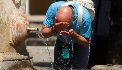 Un hombre se refresca en la fuente del Patio de los Naranjos de la Mezquita de Córdoba.