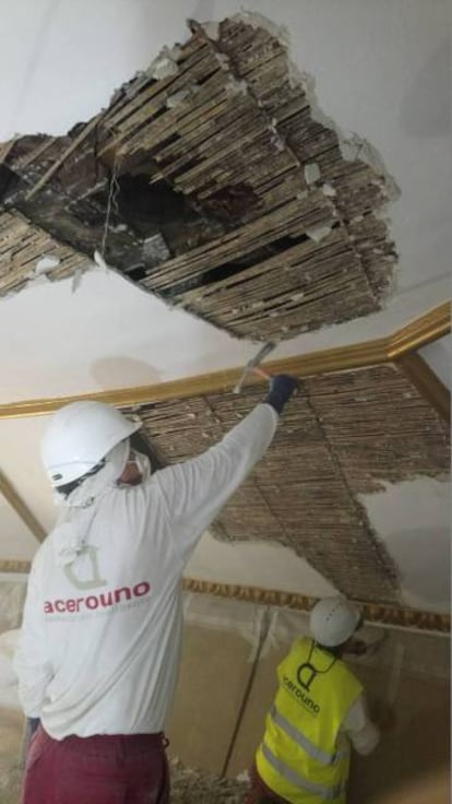 Dos trabajadores eliminan el falso techo y sacan a la luz el artesonado de la iglesia de Santa María la Blanca, en Canillejas.