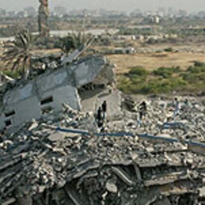 Varios palestinos caminan sobre los restos de uno de los edificios dinamitados ayer por el Ejército de Israel.