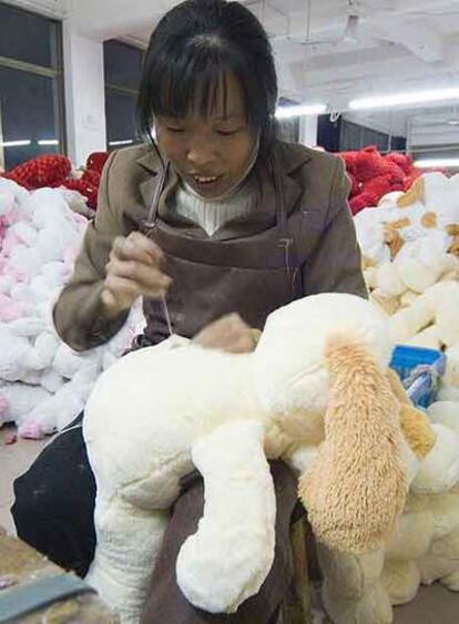Una mujer china cose muñecos de peluche en un taller chino.