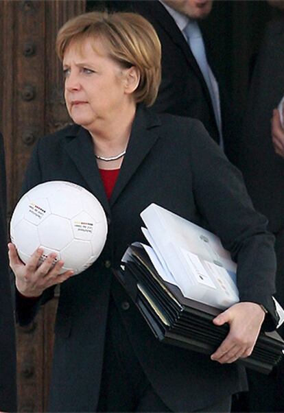 La canciller alemana, Angela Merkel, abandona una reunión en la ciudad de Genshagen con un balón en la mano.