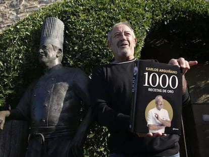 Karlos Arguiñano posa con su último libro junto a una estatua erigida en su nombre en Zarautz (Gipuzkoa).