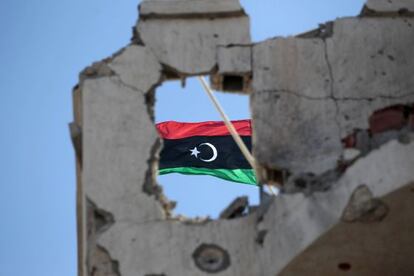 Una bandera de Libia monárquica en un edificio dañado en Sirte.