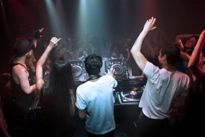 Varios DJ animan al público en una discoteca  a hacer olas.