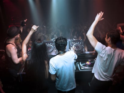 Varios DJ animan al público en una discoteca  a hacer olas.