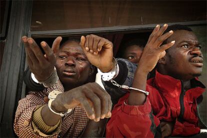 Un grupo de subsaharianos muestra sus esposas desde el autobús en el que la policía marroquí los transporta al Sáhara.