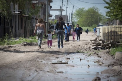 Dos mujeres y una ni&ntilde;a caminan por un barrio carenciado de Buenos Aires.