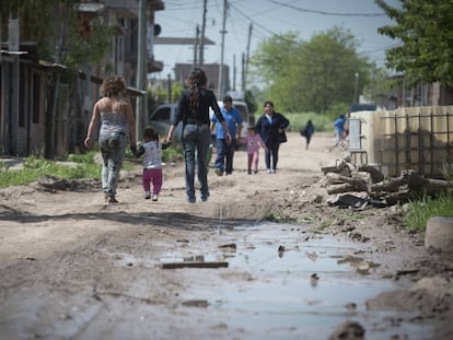 Dos mujeres y una niña caminan por un barrio carenciado de Buenos Aires.