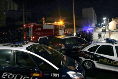 Miembros de la Policía Nacional y del cuerpo de bomberos bloquean la zona donde el joven falleció al caer a una hoguera.