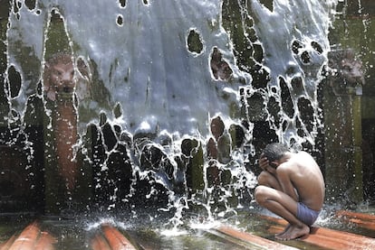 Un niño juega en una fuente durante un día caluroso en Nueva Delhi (India).