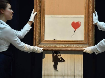 Empregados da Sotheby’s carregam a obra semidestruída de Banksy.