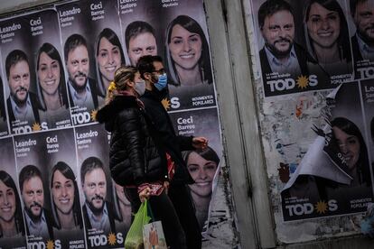 Una pareja camina frente a un cartel con la cara de Leandro Santoro, primer precandidato a diputado por el Frente de Todos, el 9 de septiembre de 2021, en la ciudad de Buenos Aires