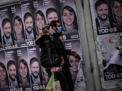 Una pareja camina frente a un cartel con la cara de Leandro Santoro, primer precandidato a diputado por el Frente de Todos, el 9 de septiembre de 2021, en la ciudad de Buenos Aires
