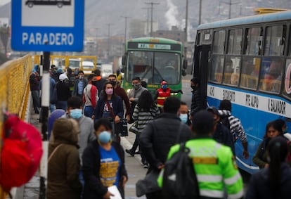 Varias personas pasan frente a una parada de autobuses en Lima (Perú).