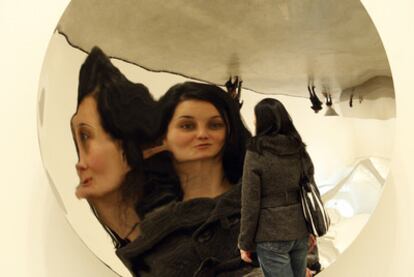 Una mujer se refleja en la obra <b><i>Poniendo el mundo del revés,</b></i> en la exposición de Anish Kapoor.