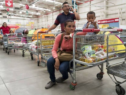 Una familia hace fila para comprar v&iacute;veres en un supermercado en Caracas.