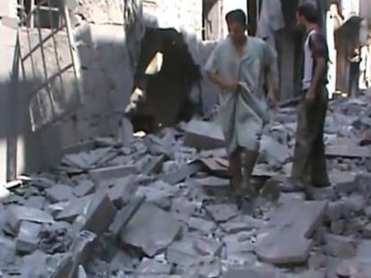 Fotograma de un vídeo facilitado por la oposición que muestra a dos hombres caminando sobre los escombros en la calle de una zona de Alepo.
