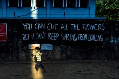 Los niños juegan con pistolas de juguete junto a una pancarta que con la leyenda "Puedes cortar todas las flores, pero no puedes impedir que llegue la primavera", colocada por activistas en protesta contra el golpe militar en Yangon (Myanmar), el 11 de abril de 2021.