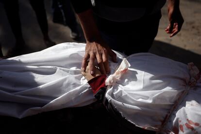 Un hombre toca la mano de un niño muerto en un bombardeo israelí sobre Jan Yunis en la franja de Gaza.