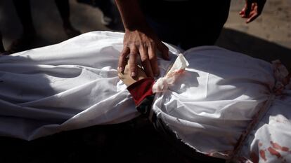 Un hombre toca la mano de un niño muerto en un bombardeo israelí sobre Jan Yunis en la franja de Gaza.