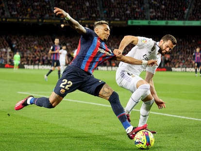 Raphinha trata de progresar con el balón mientras Nacho le agarra durante el Barcelona-Real Madrid (2-1) de este domingo.