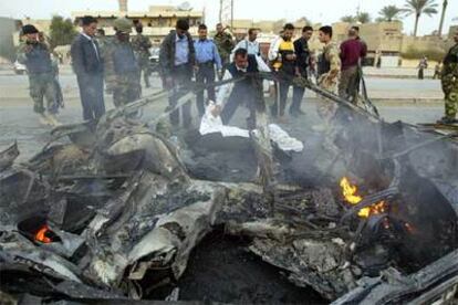 Un policía iraquí cubre el cadáver de un suicida que hizo estallar un coche ayer en Bagdad.