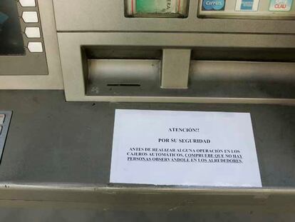 Un cartel alerta a quienes vayan a sacar dinero del cajero de un banco en la calla de Ríos Rosas.